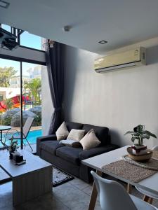 a living room with a couch and a table at Utopia Lofts by Sabai Sands in Nai Harn Beach