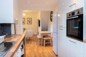 a kitchen with white appliances and a table with chairs at Goulder House- Close To Motorway & CO-OP Live in Manchester