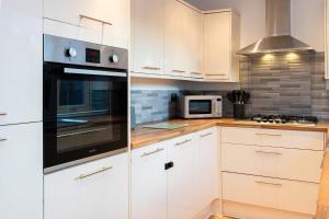 a kitchen with white cabinets and a stove top oven at Goulder House- Close To Motorway & CO-OP Live in Manchester