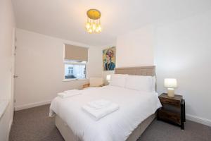 a bedroom with a large white bed and a chandelier at Goulder House- Close To Motorway & CO-OP Live in Manchester