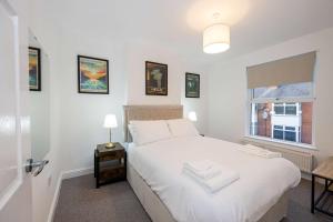 a bedroom with a white bed and a window at Goulder House- Close To Motorway & CO-OP Live in Manchester +16 photos