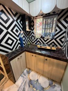 a kitchen with a black and white patterned wall at Magic holiday home in Matheran