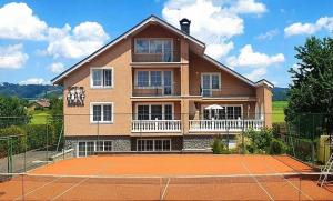 a house with a tennis court in front of it at Penzion rodina in Chornice