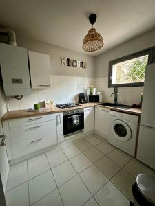 een keuken met witte kasten en een wasmachine bij Joli studio les pieds dans l eau avec place de Parking gratuite in Bandol +7 foto's