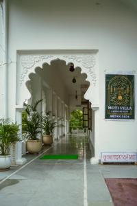 a hallway of a building with potted plants and a sign at Moti Villa in Jāmb