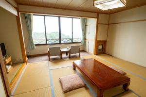 ein Wohnzimmer mit Tisch und großem Fenster in der Unterkunft 星と緑のロマン館 in Ogawa