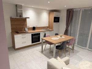 a kitchen with a wooden table and chairs in a room at Murmure de rose in Rosnoën