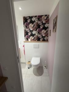 a bathroom with a toilet with a floral wallpaper at Murmure de rose in Rosnoën +7 photos