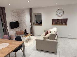 a living room with a couch and a clock on the wall at Murmure de rose in Rosnoën