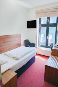 een slaapkamer met een bed, een tv en een stoel bij Dancenter Hotel Jomfru Ane in Aalborg