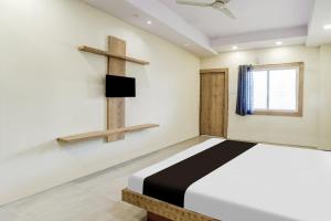 a bedroom with a bed and a cross on the wall at Hotel O katyayani in Indore