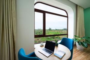 una camera con tavolo, computer portatile e finestra di VinaEcolife Lodge a Ba Tri