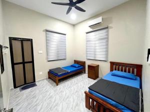 una camera da letto con due letti e un ventilatore a soffitto di Baba Homestay a Macang