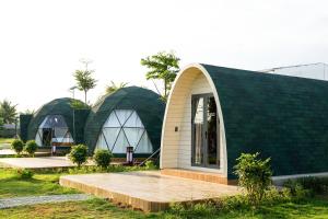 a green and white building with a wooden ramp in front at VinaEcolife Lodge in Ba Tri