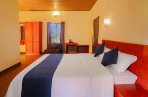 a bedroom with a large white bed with blue pillows at Rippon Mount Resorts in Meppādi +45 photos