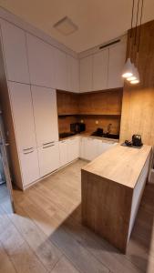 a kitchen with white cabinets and a wooden table at Apartament Skarbowa 2 in Leszno