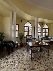 a living room with tables and chairs and windows at Prangan - The Villa in Chākdaha