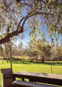 a wooden bench sitting under a tree in a park at Harrington Holiday House in Harrington