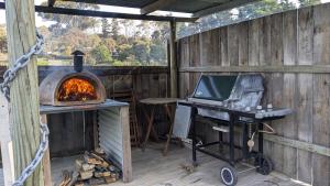 a wood fired oven on a patio with a grill at Bonnie Brae Retreat in Swansea