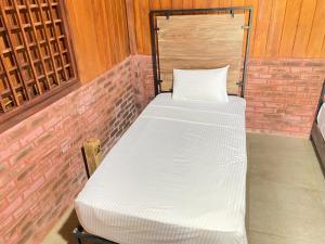 a bed in a room with a brick wall at The Thinnai Farm in Jaffna