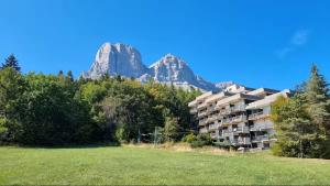 a large apartment building with mountains in the background at Col de L'Arzelier in Château-Bernard