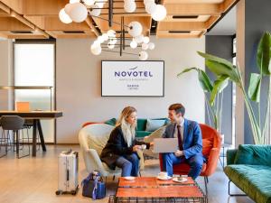 two people sitting in chairs in a room with a laptop at Novotel Parma Centro in Parma