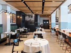a dining room with white tables and chairs at Novotel Parma Centro in Parma