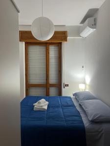 een slaapkamer met een bed met blauwe lakens en een lamp bij alta marea sardegna in Portoscuso