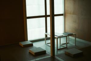 een tafel en twee krukken voor een raam bij A&A Okayama in Okayama
