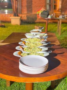 a wooden table with white bowls and plates on it at The Thinnai Farm in Jaffna