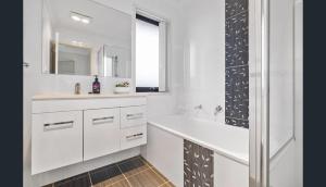 a white bathroom with a sink and a mirror at Four-bedroom house in Gungahlin