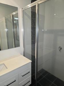 a bathroom with a shower and a sink and a mirror at Four-bedroom house in Gungahlin