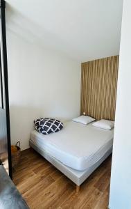 a bed in a small room with white sheets at Bel Air Appartement in Niort