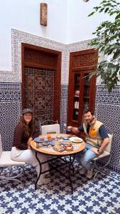een groep mensen die rond een tafel zitten met eten erop bij Dar Abdesalam in Fès