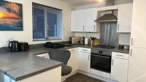 una cucina con mobili bianchi e un forno a piano cottura di Spacious Luxurious Serviced Accommodation 5 a Bushbury