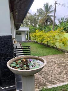 a bird bath filled with water and flowers in a yard at JHome in Kurunegala