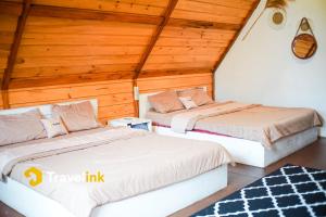 two beds in a room with wooden ceilings at Quenz Cabin By Travelink in Dieng
