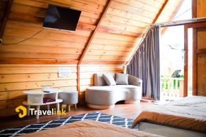 a bedroom with a couch and a tv on the ceiling at Quenz Cabin By Travelink in Dieng