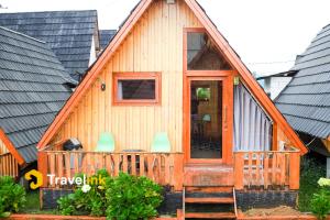 a wooden house with a porch and two chairs at Quenz Cabin By Travelink in Diyeng +1 photo