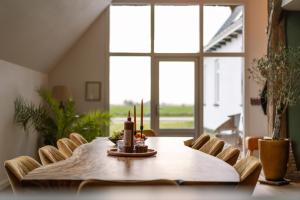 een eetkamer met een tafel en stoelen en een raam bij B&B Lindehoeve Texel in Den Hoorn