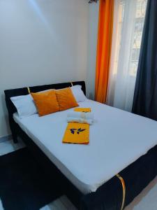 a bed with orange and white pillows and a window at Mwangaza in Mombasa
