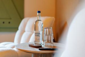 een fles water op een tafel naast een glas bij B&B Lindehoeve Texel in Den Hoorn +60 foto's