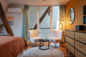 een slaapkamer met een bed, twee stoelen en een tafel bij B&B Lindehoeve Texel in Den Hoorn