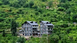 a large building on the side of a hill at Manali Se - Your Home in the Pines in Jagatsukh