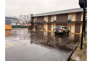 a car parked in a parking lot in front of a building at The Queen B Motel, Detroit-Warren in Warren