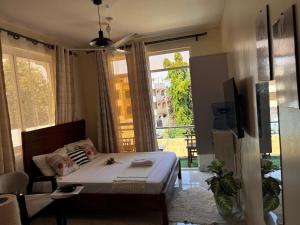 een slaapkamer met een bed en een groot raam bij Hosting by Vee in Mtwapa