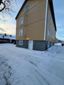 a large building with snow on the ground next to it at Aurora Apartment 7 in Kiruna