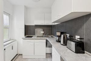 eine Küche mit weißen Schränken und einer Spüle und einer Mikrowelle in der Unterkunft Büchner 52-1 in Gera