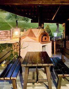 een picknicktafel met een houtgestookte oven op een terras bij CASA DEL CANTA in Borgomale