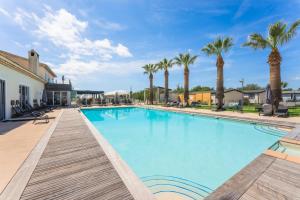 a large swimming pool with palm trees in the background at Holiday Marina Resort in Grimaud